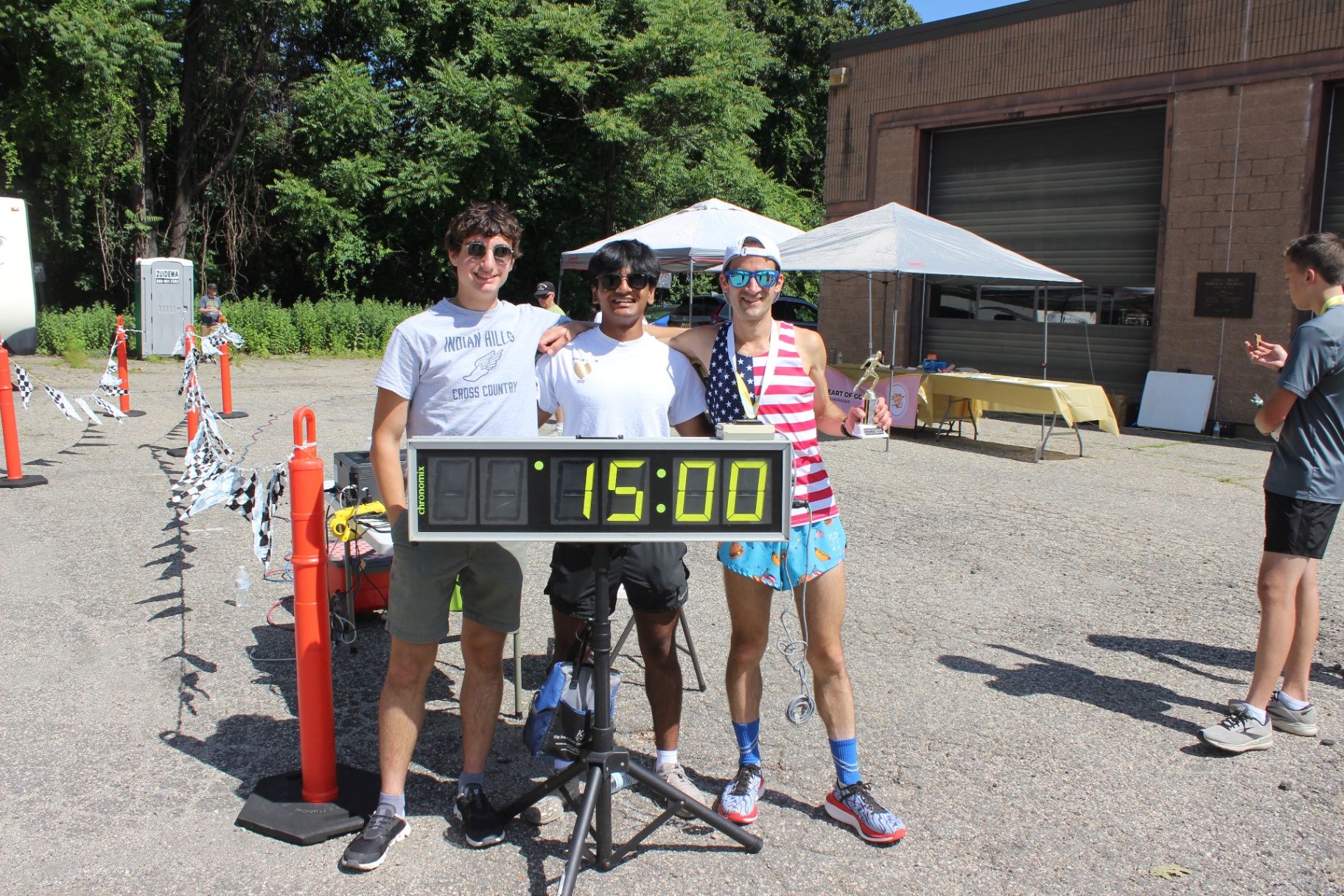 Three race organizers standing behind the digital race clock at the Heart of Gold 5K.