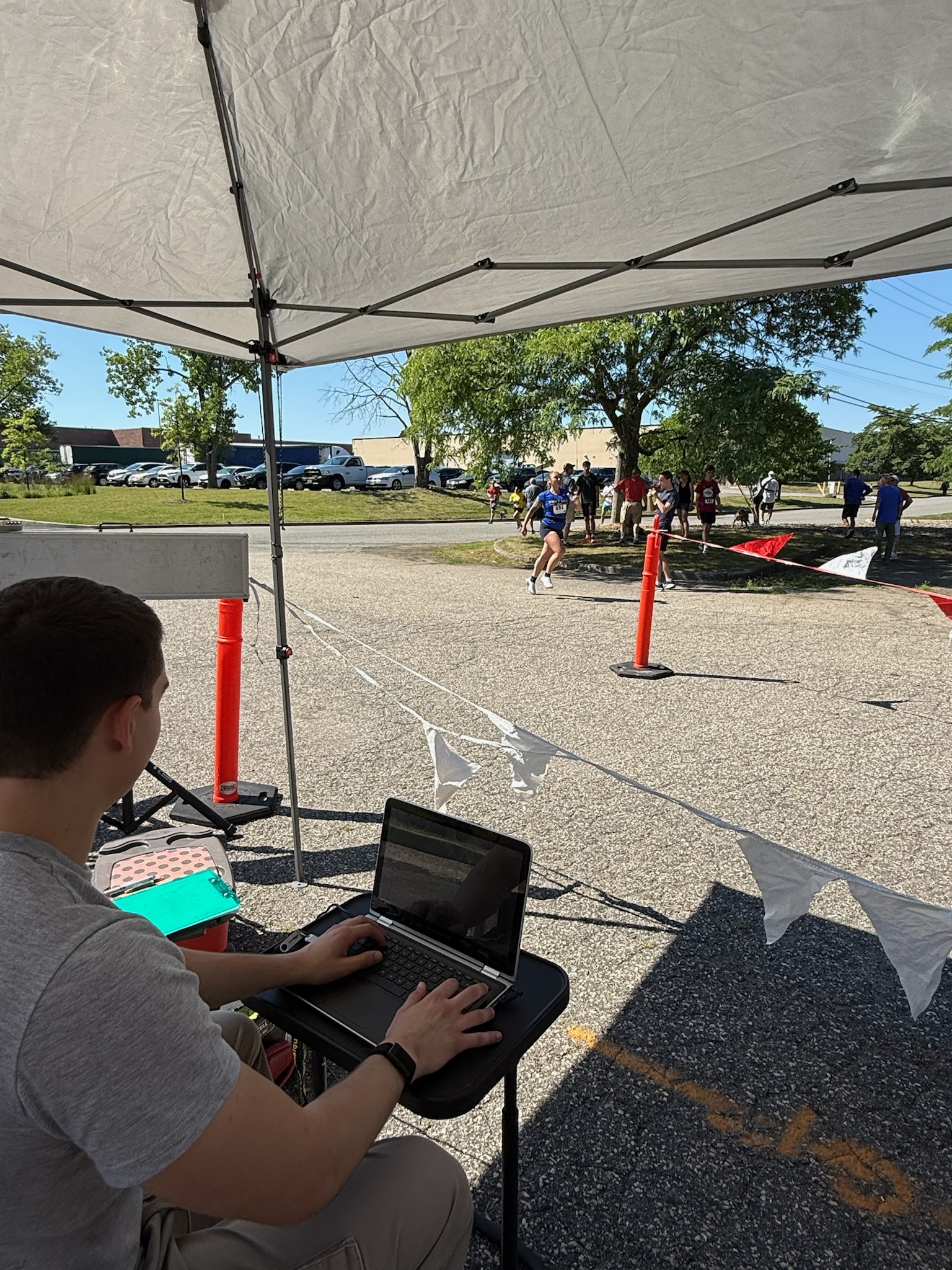A volunteer working on a laptop at the timing station under the event tent at the Heart of Gold 5K.