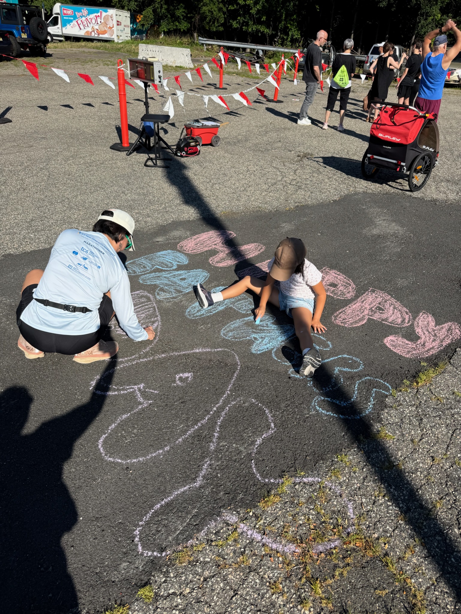 A child drawing chalk art on the pavement near the race course at the Heart of Gold 5K.