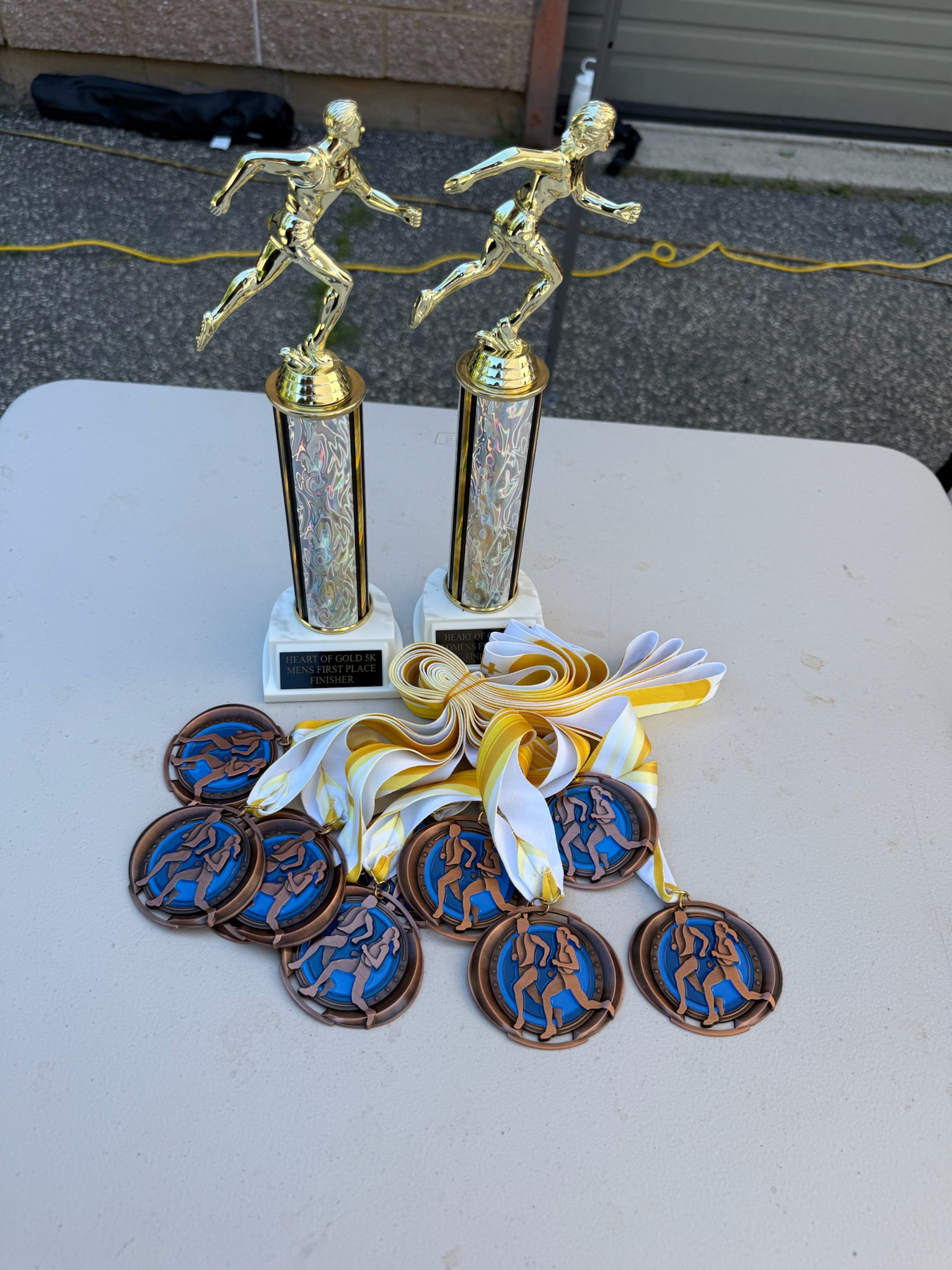 Runner medals and first-place trophies laid out for the Heart of Gold 5K awards ceremony.
